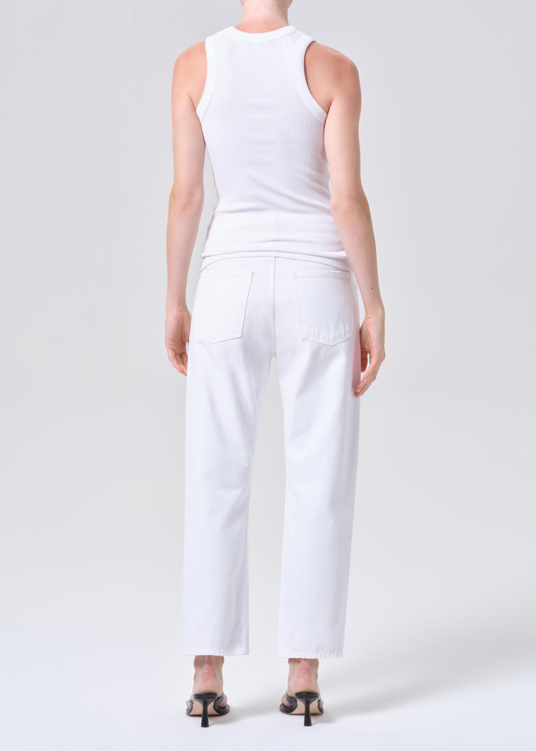 Person wearing a white sleeveless top and pants on a plain background