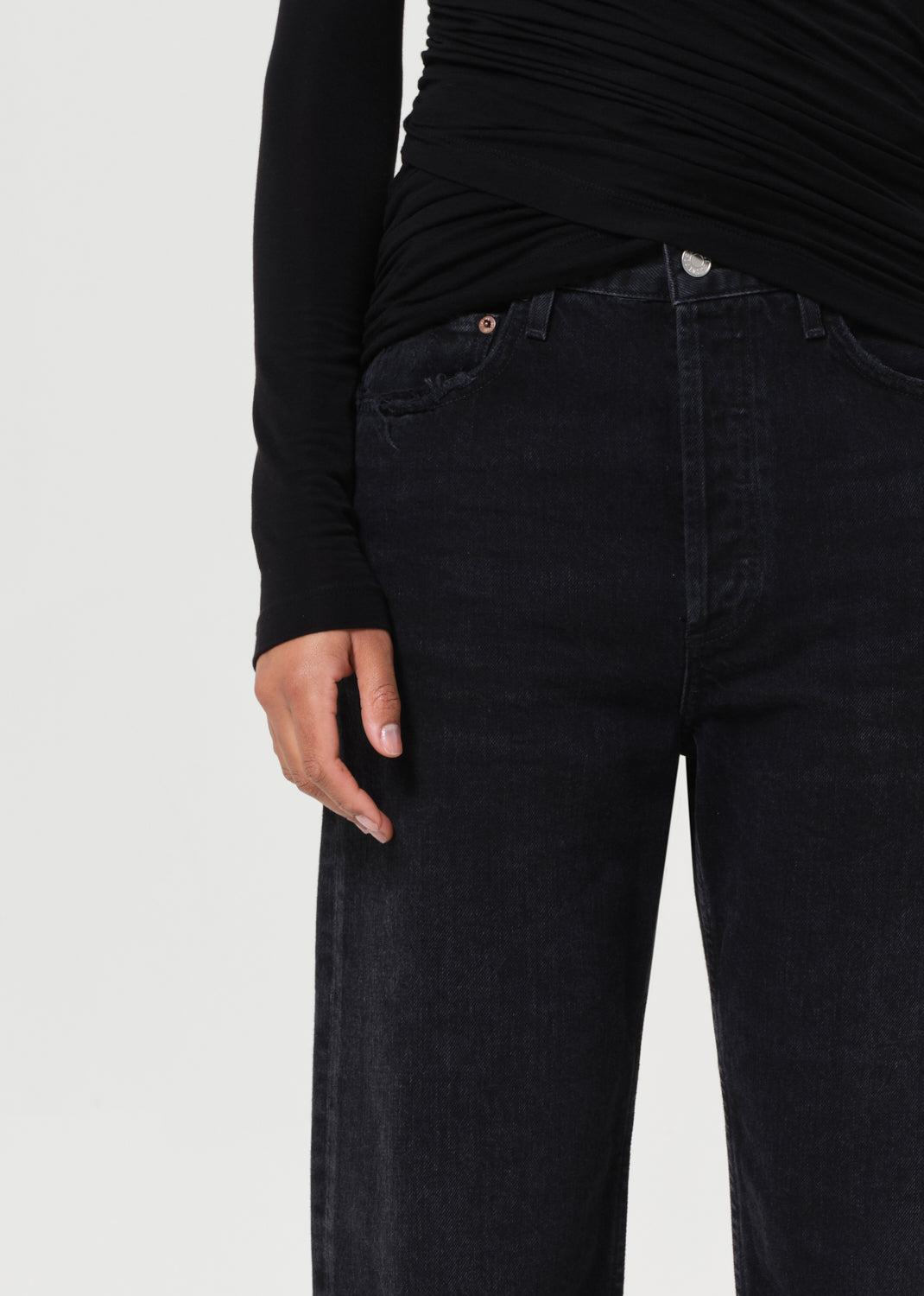 Person wearing black jeans and a black long-sleeve top on a light gray background