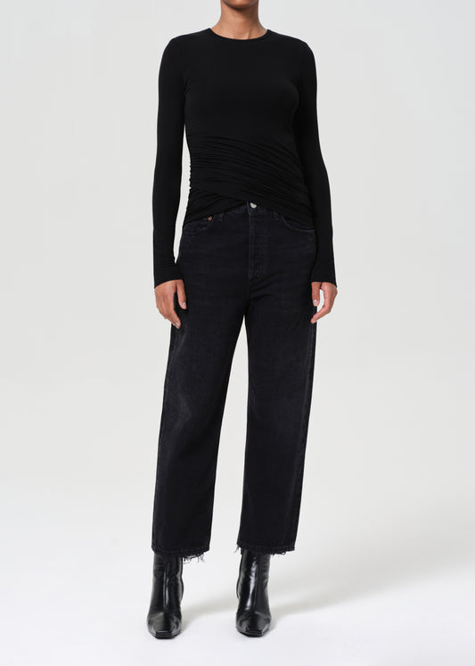 Person wearing a black long-sleeve top and black pants on a white background