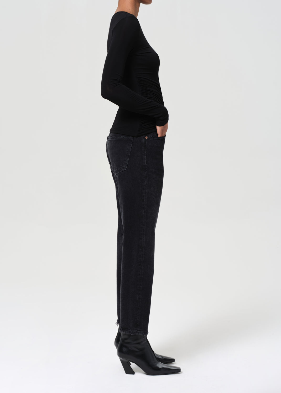 Person wearing a black sweater and dark jeans on a white background