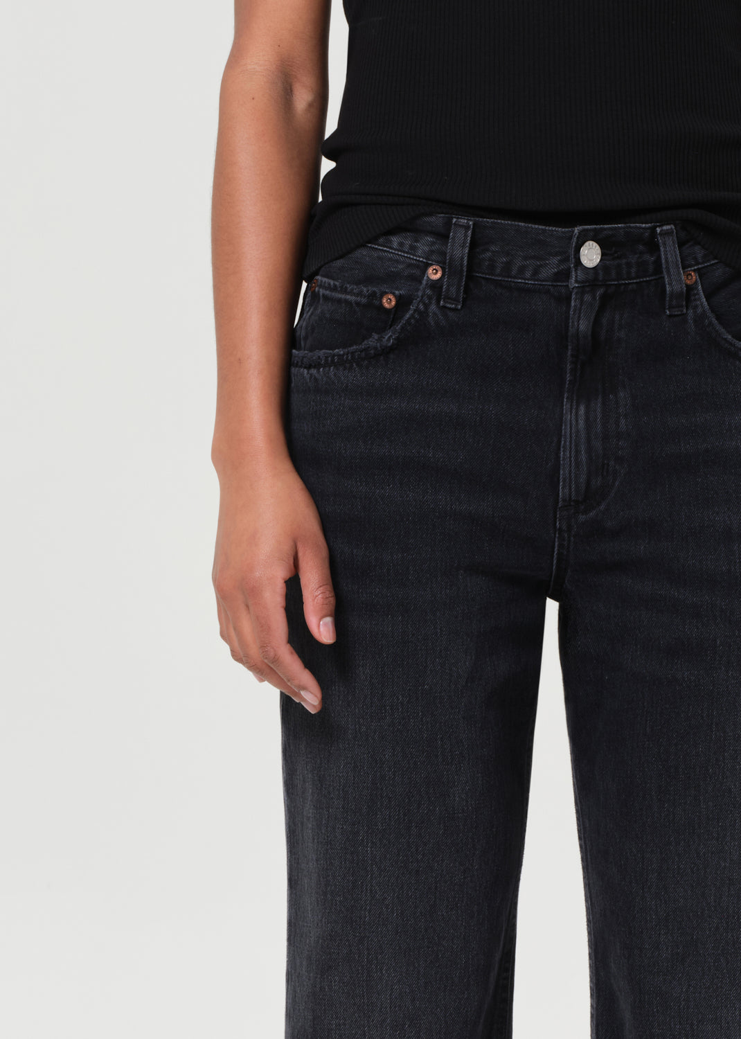 Person wearing black jeans on a plain background