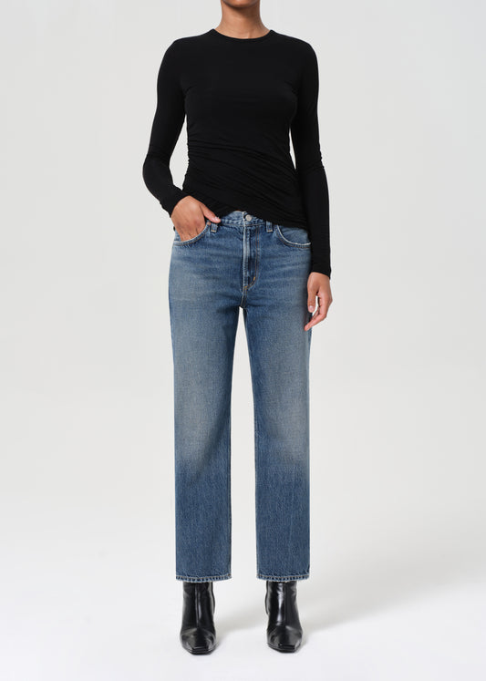 Person wearing a black long-sleeve top and blue jeans on a white background