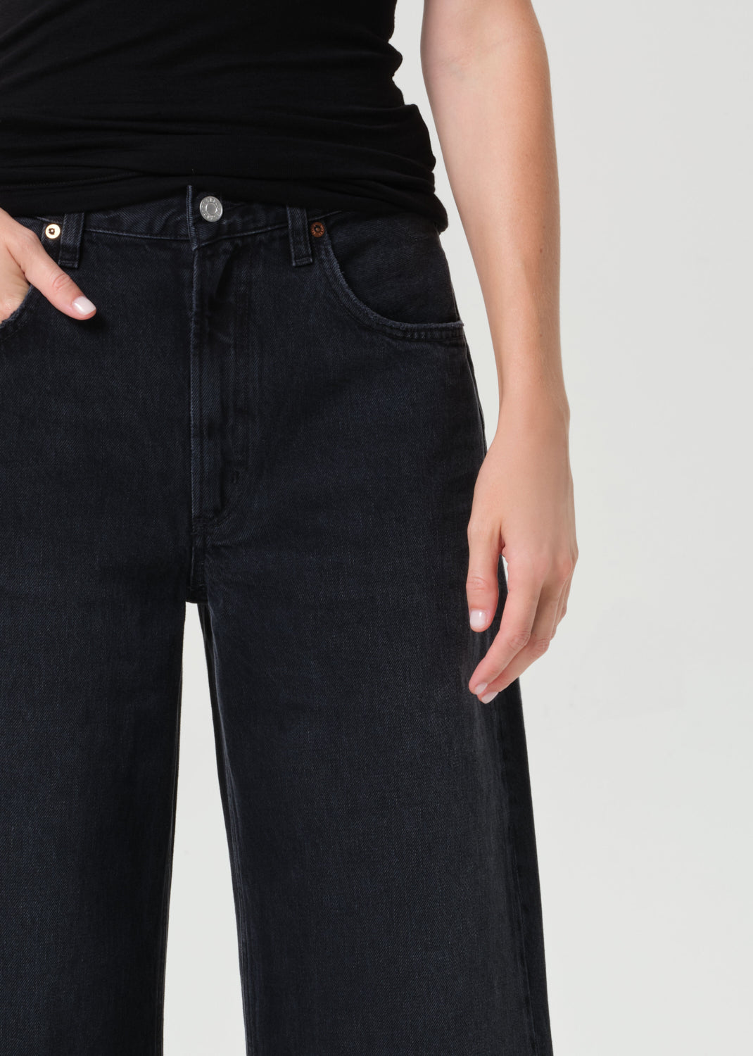 Person wearing black jeans on a plain background
