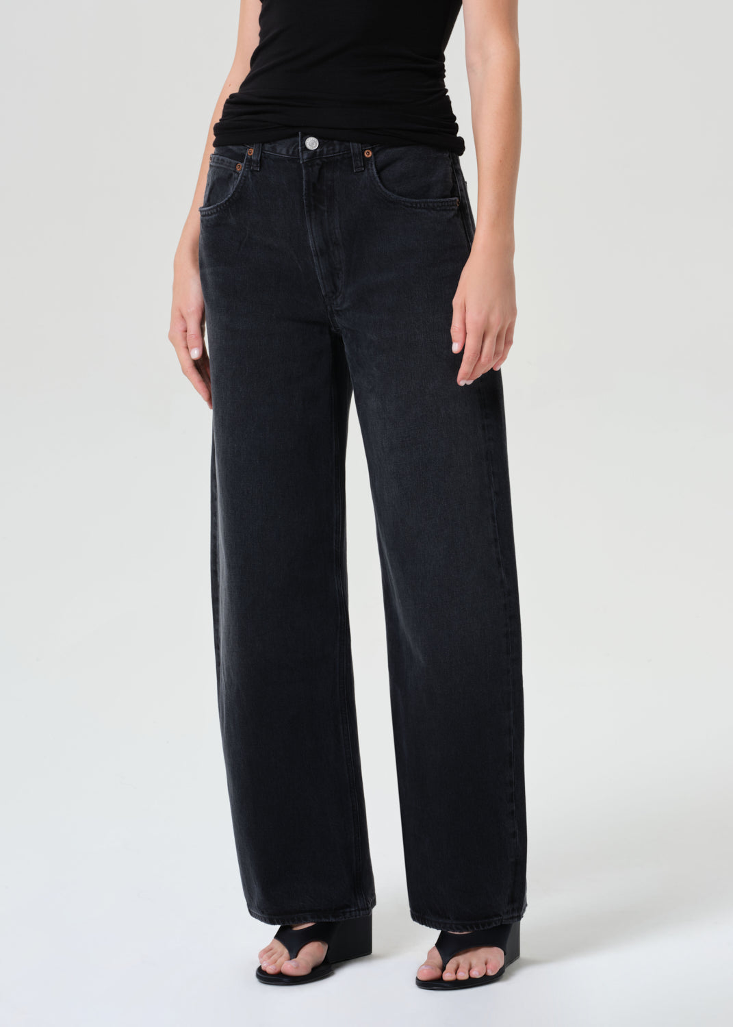 Person wearing black jeans and a black top on a white background