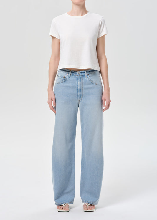 Person wearing light blue jeans and a white t-shirt on a white background