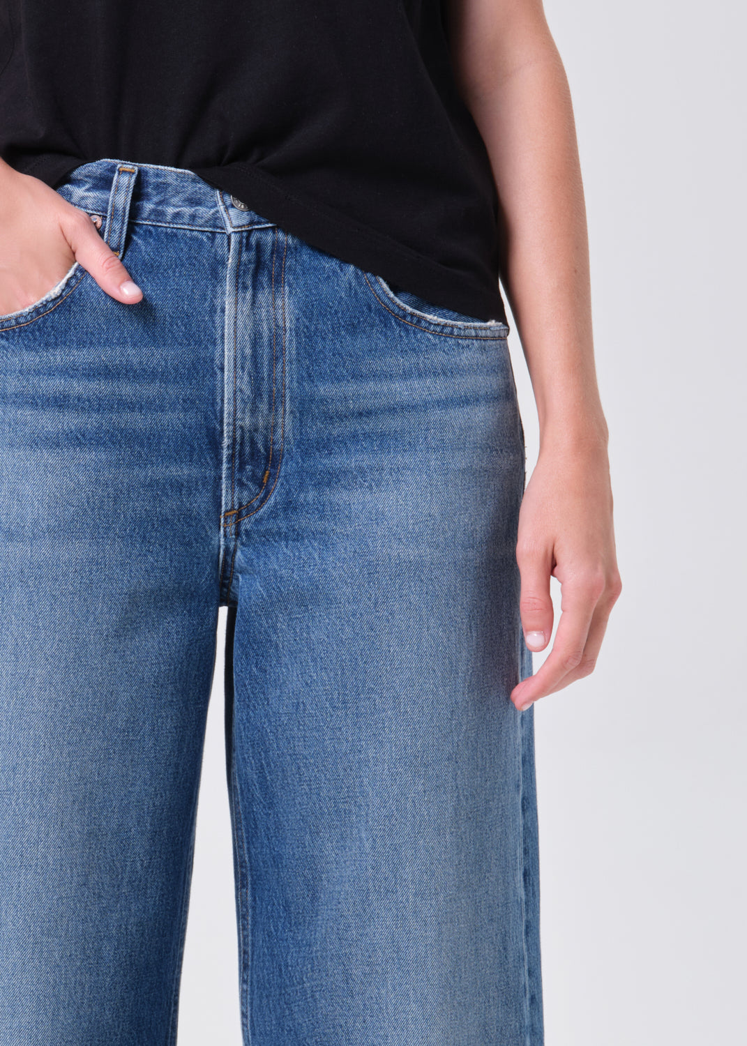 Person wearing blue jeans with a plain background