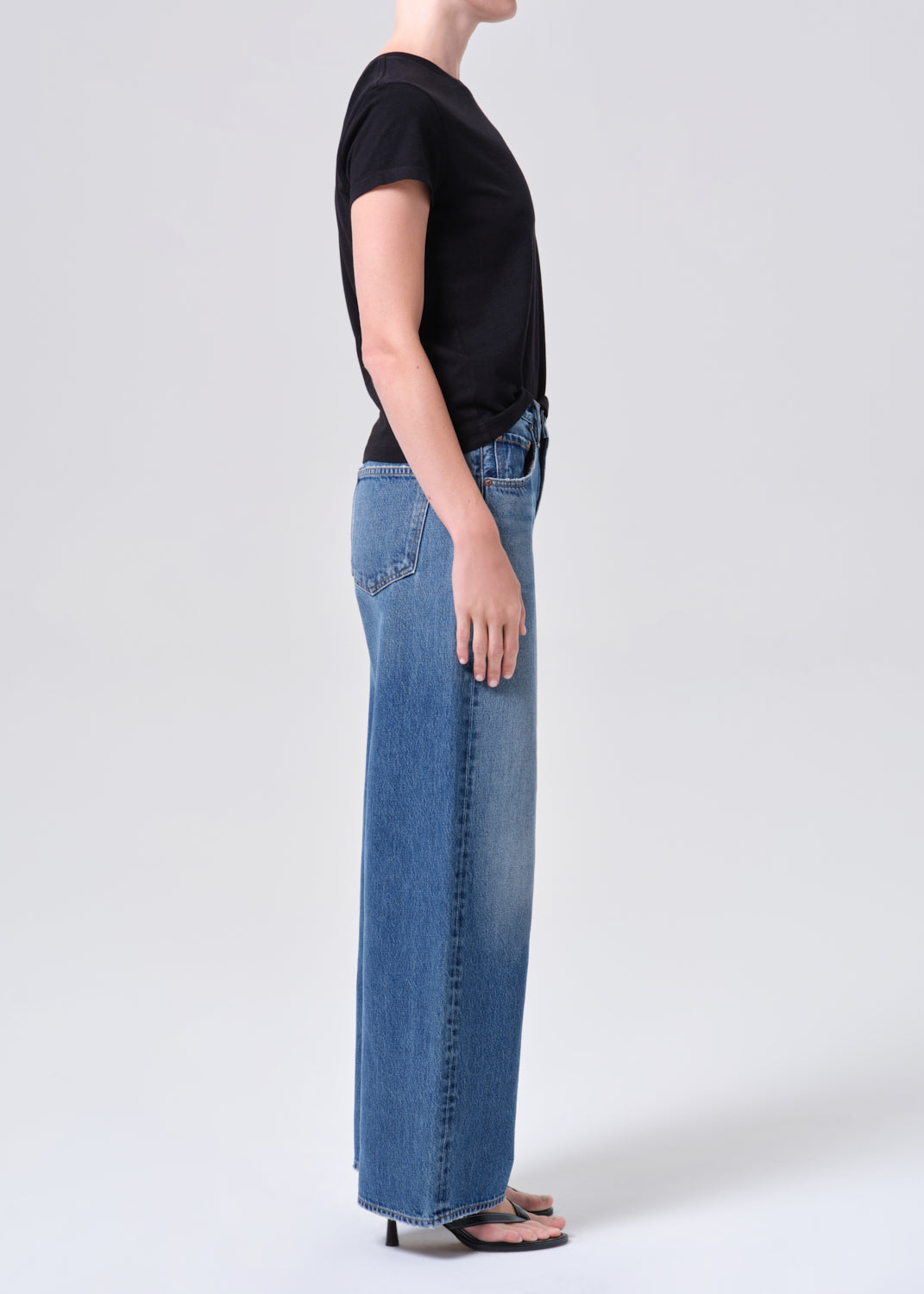 Person wearing a black t-shirt and blue jeans on a white background