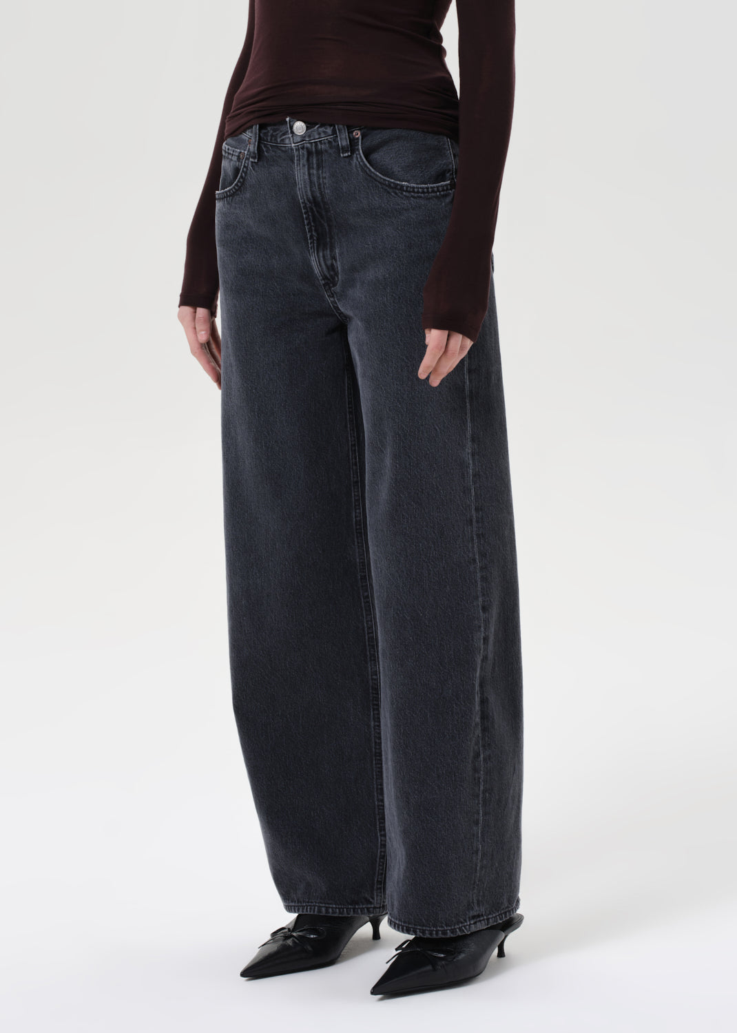 Person wearing wide-leg jeans and a dark top on a white background