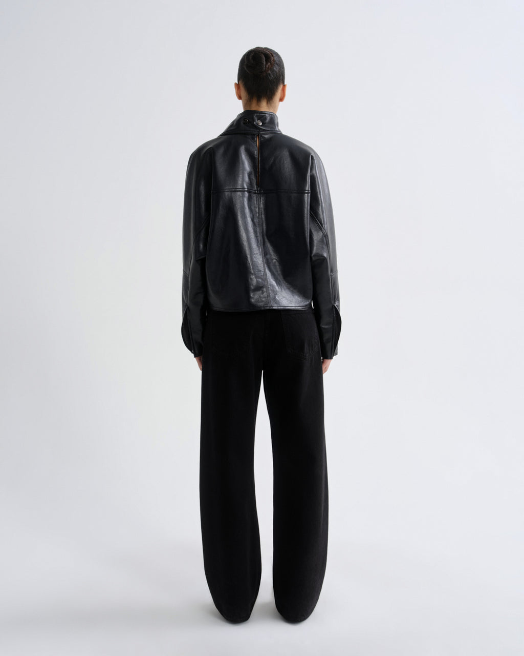 Person wearing a black leather jacket and pants on a white background