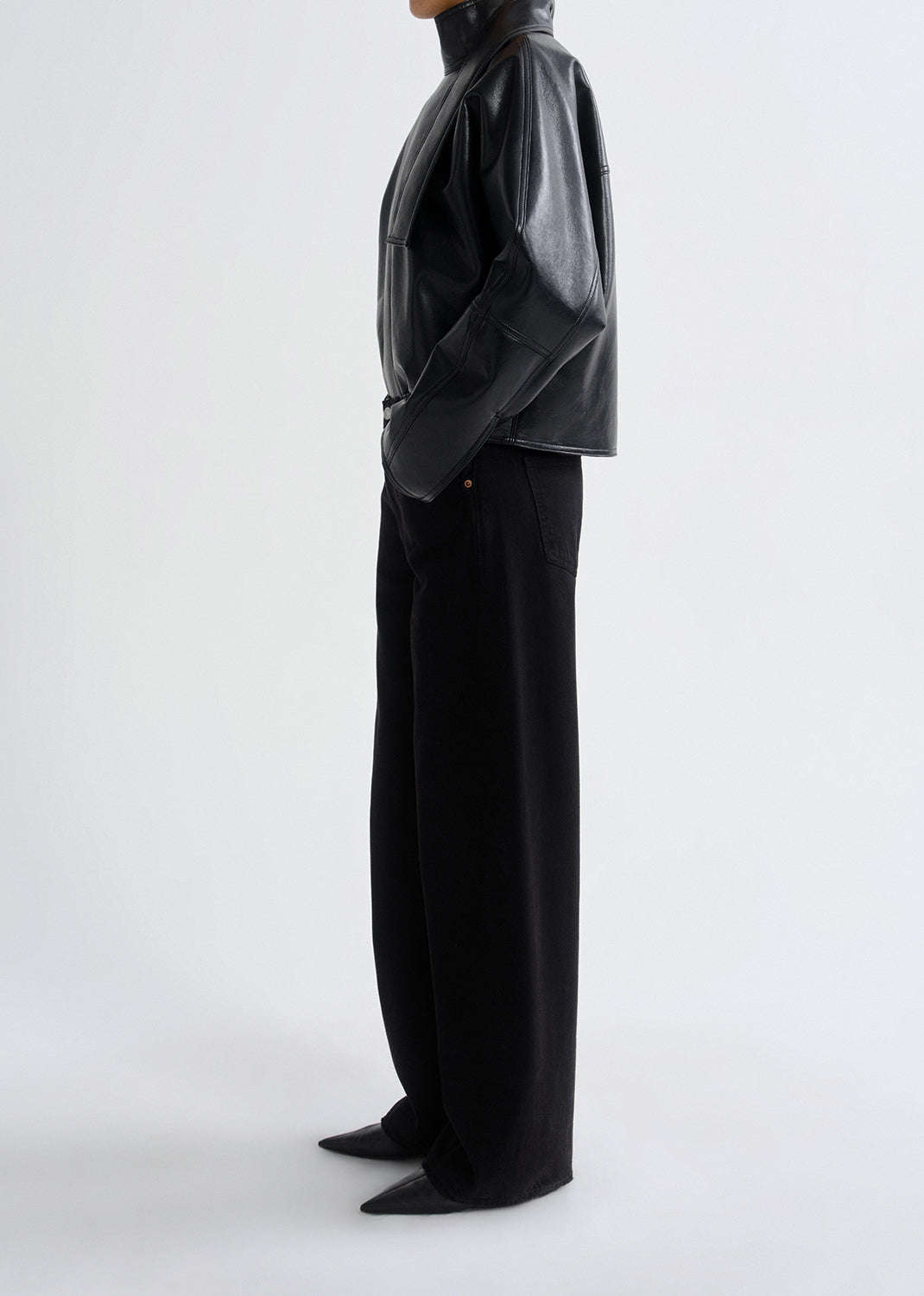 Person wearing a black vinyl jacket and pants on a grey background