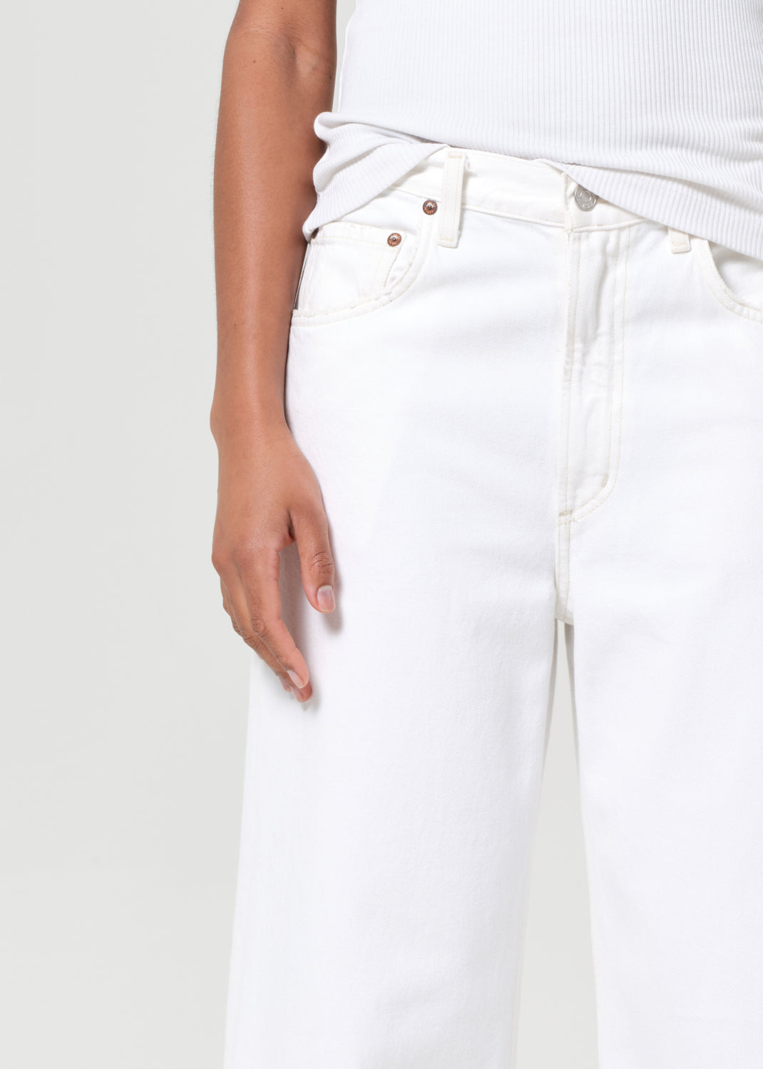 White jeans worn by a person on a light gray background