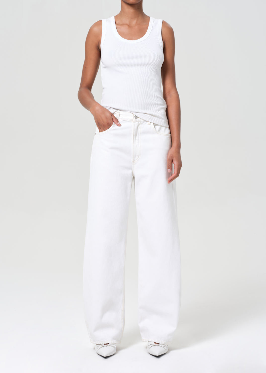 Person wearing a white tank top and white pants on a plain background
