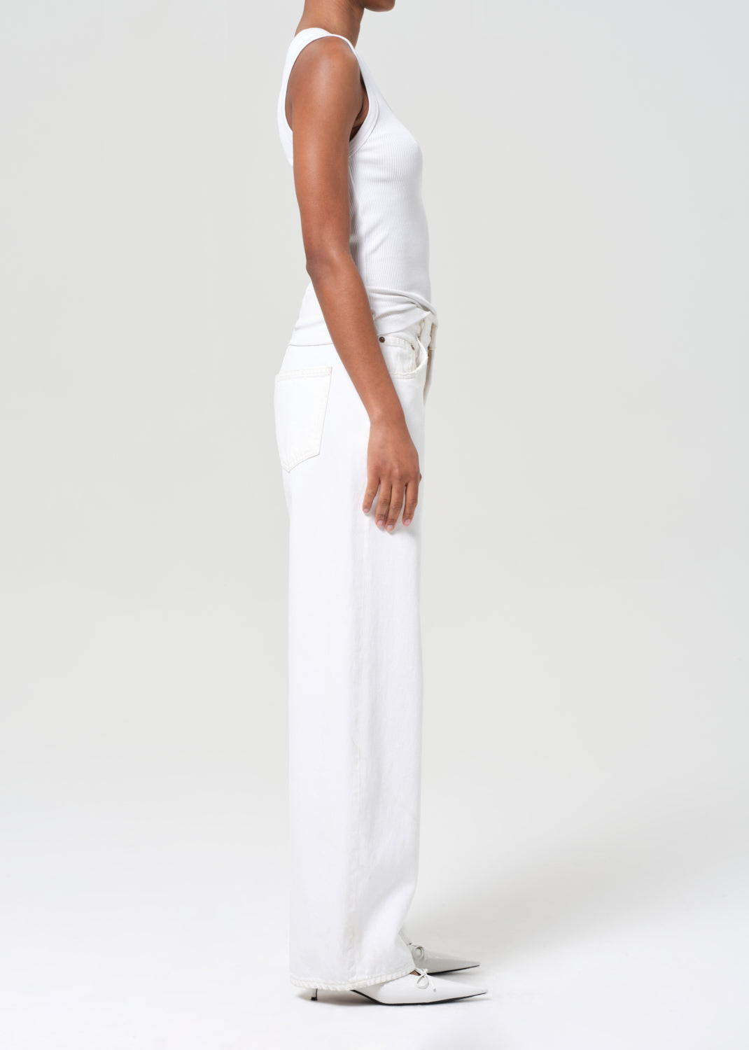 Person wearing a white sleeveless top and pants on a light gray background