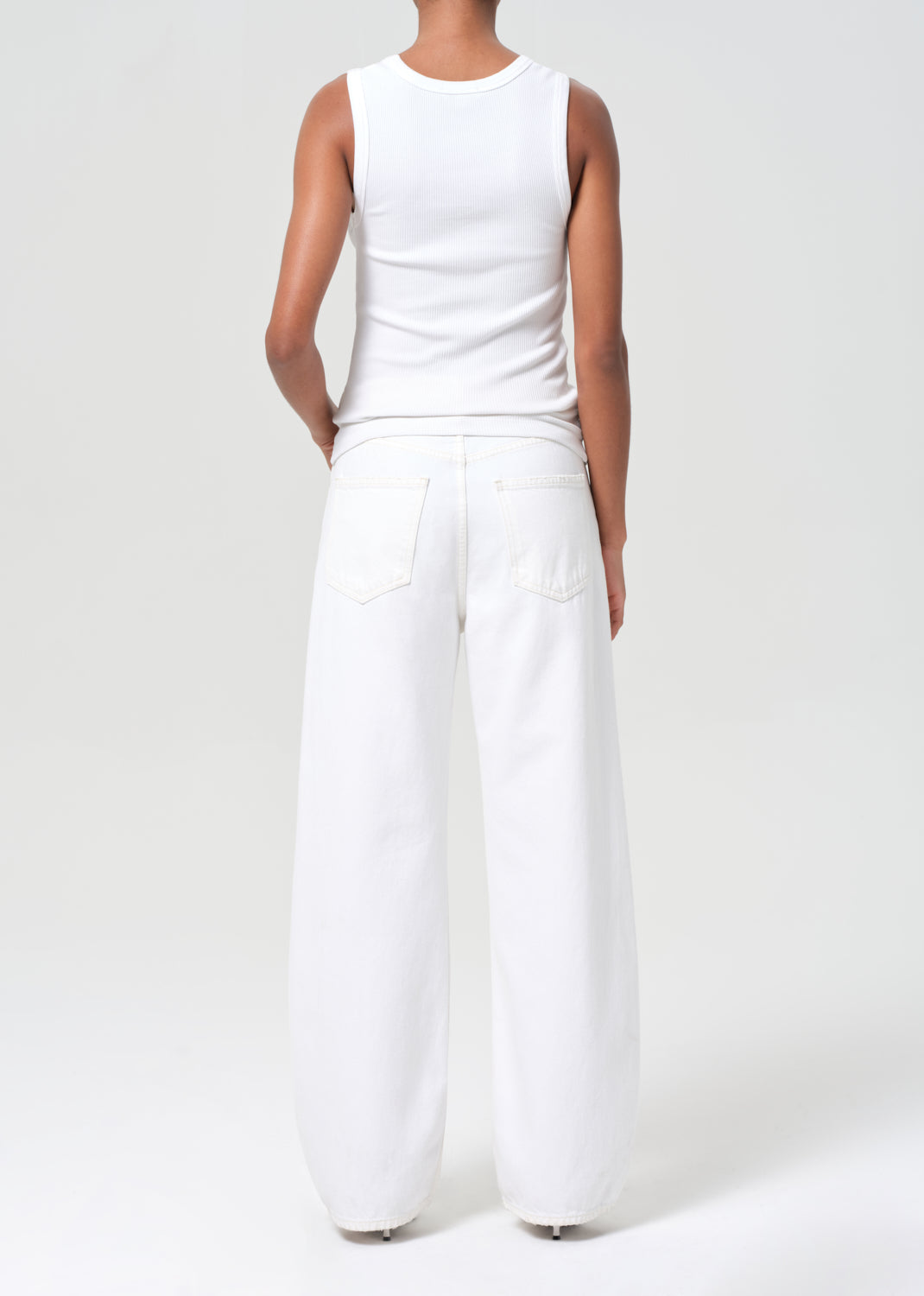 Person wearing a white sleeveless top and wide-leg pants on a white background