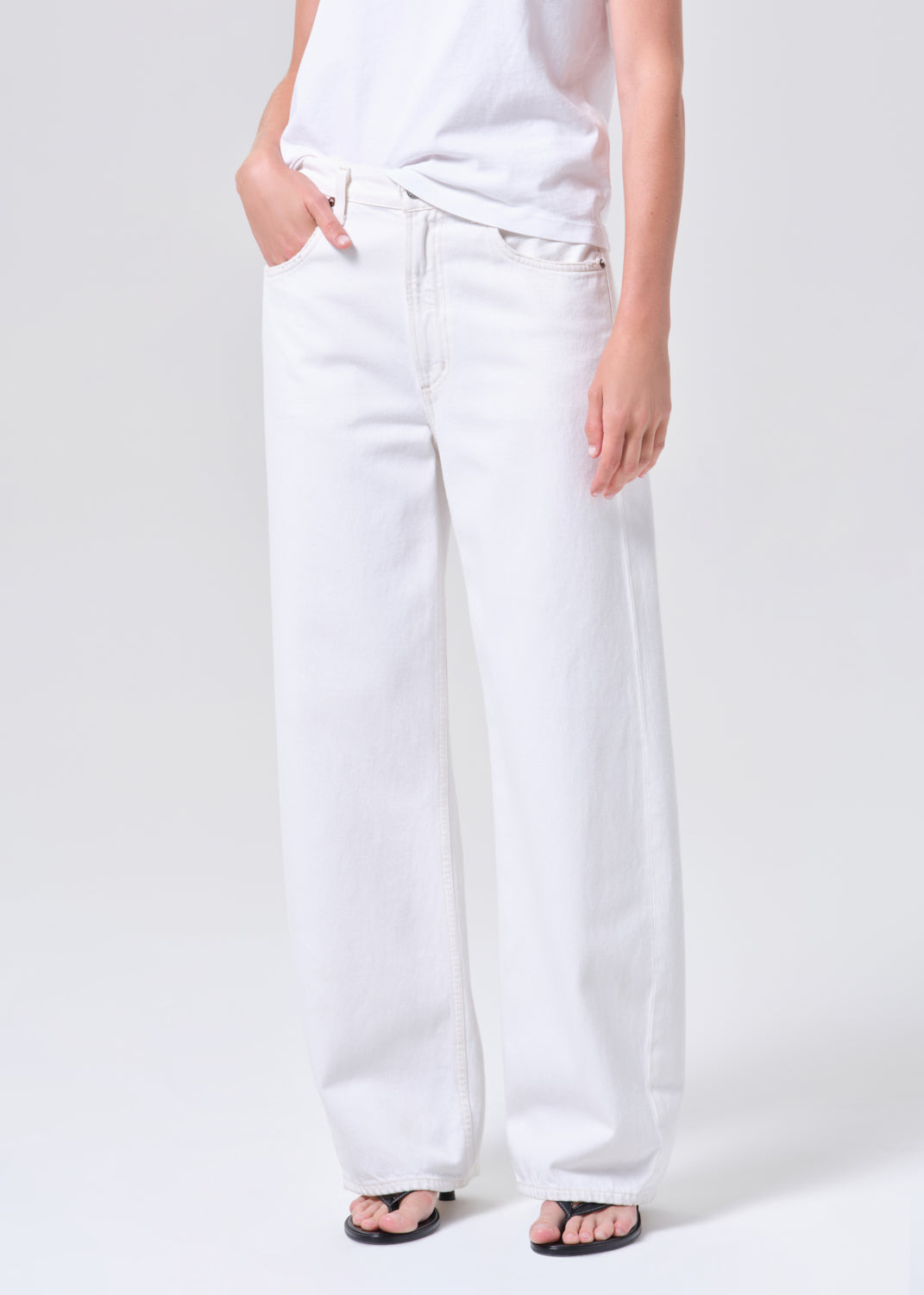 Person wearing white jeans on a plain background