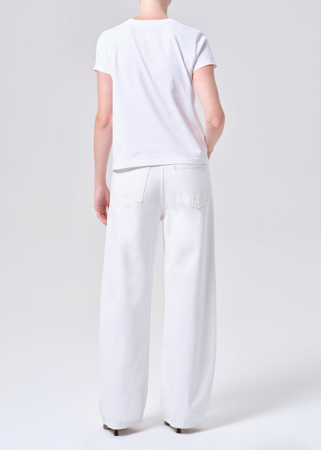 Person wearing a white t-shirt and wide-leg pants on a plain background
