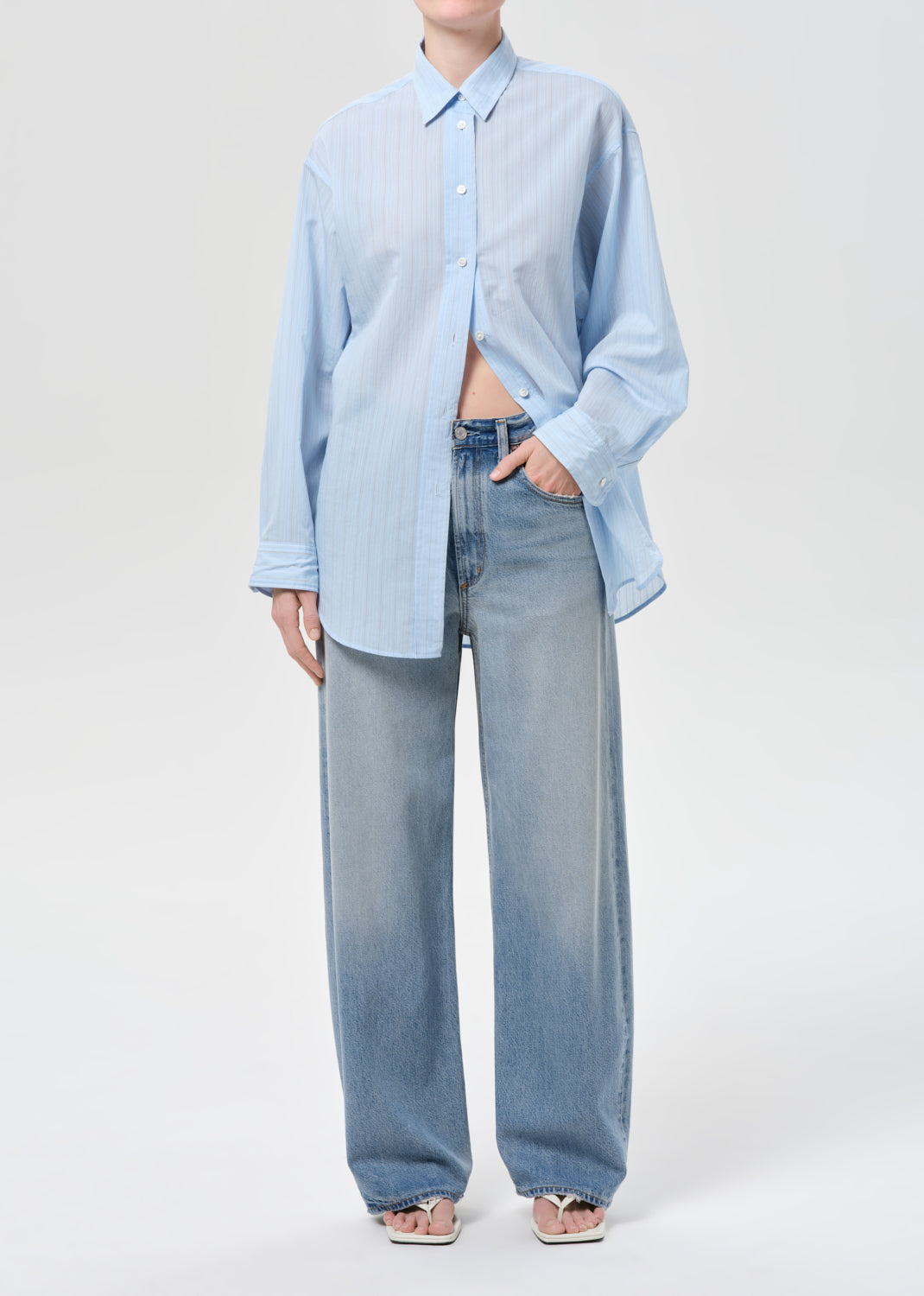 Person wearing a light blue shirt and jeans on a white background