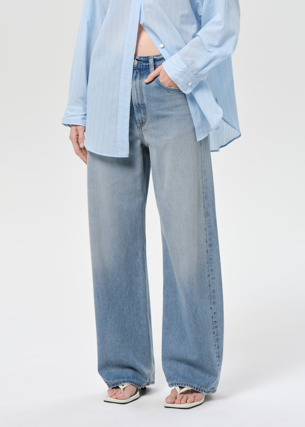 Person wearing a light blue shirt and jeans on a white background