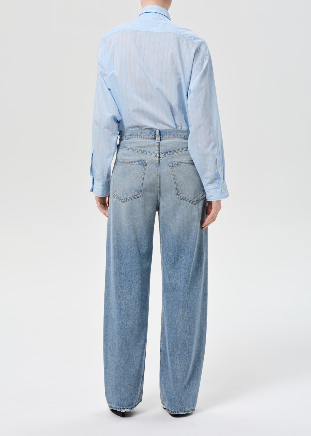Person wearing a light blue denim jumpsuit on a white background