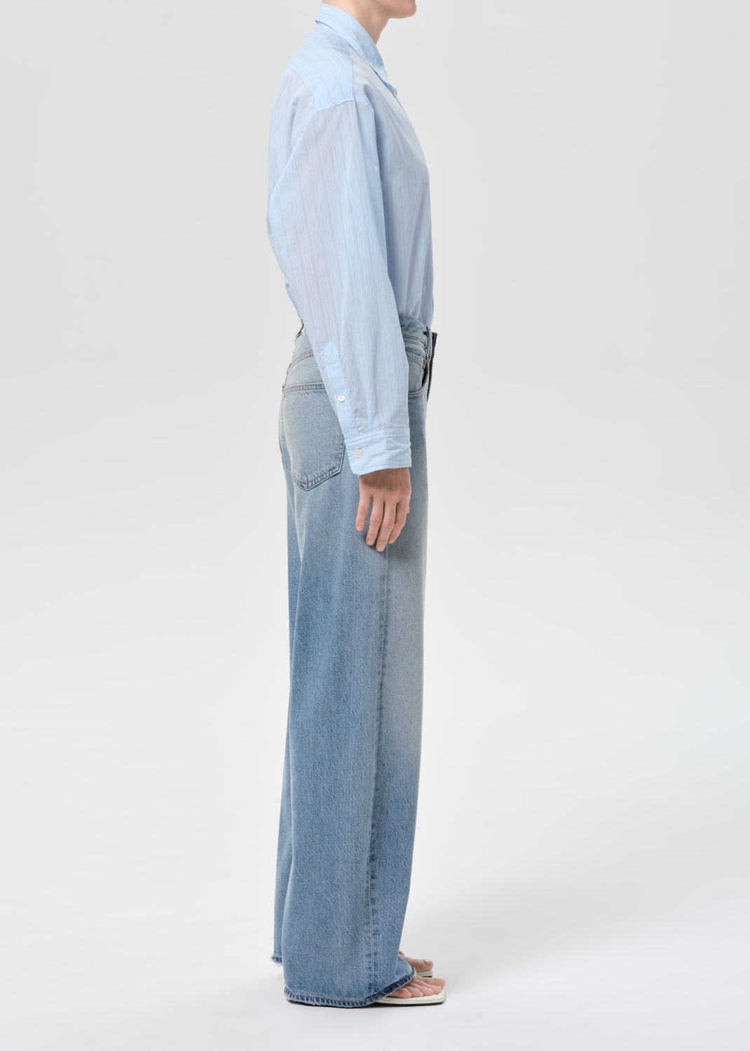 Person wearing a light blue shirt and jeans on a white background
