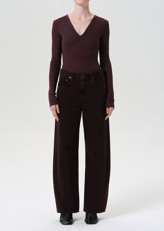 Person wearing a brown long-sleeve top and wide-leg pants on a white background