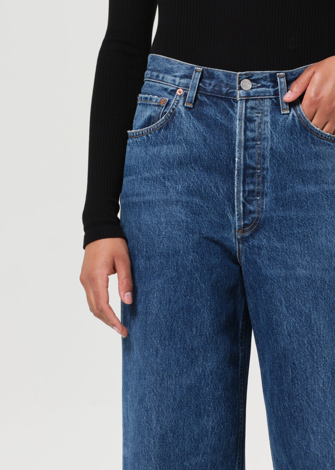 Close-up of blue jeans worn by a person on a light gray background