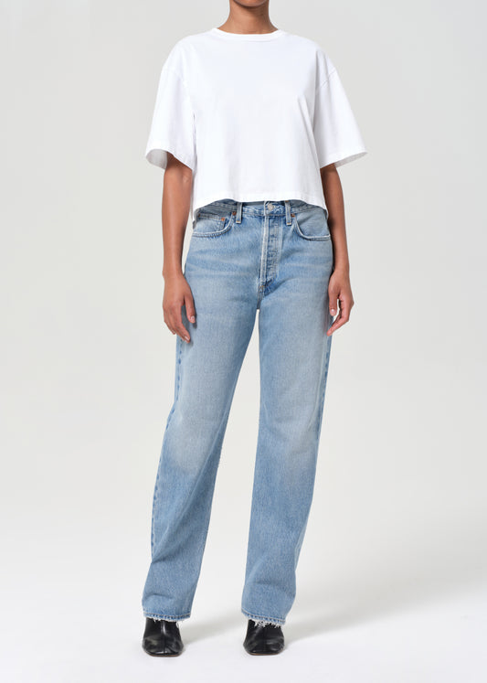 Person wearing light blue jeans and a white t-shirt on a plain background