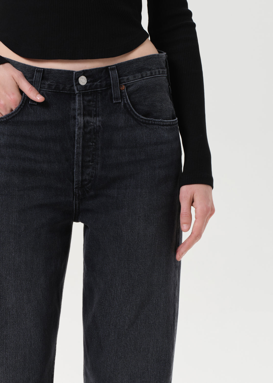 Person wearing black jeans and a black long-sleeve top on a white background