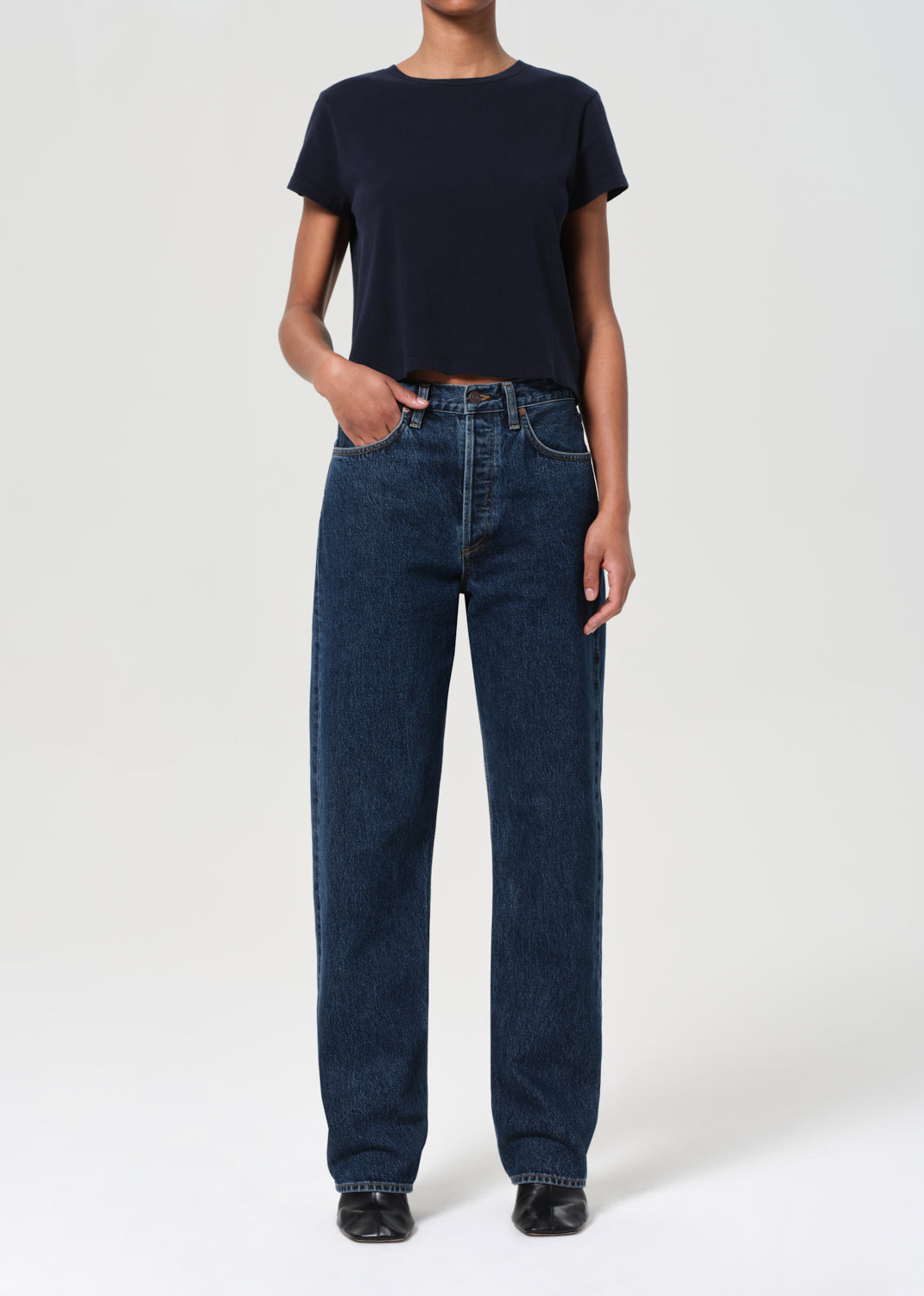 Person wearing a navy t-shirt and blue jeans on a white background