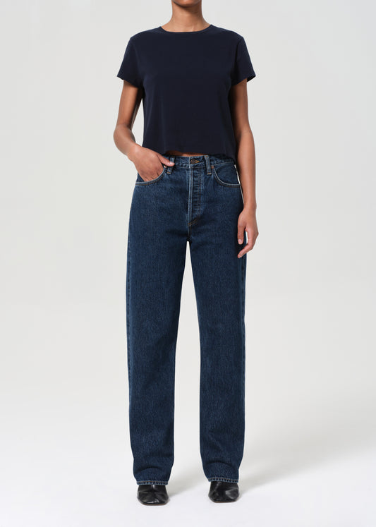 Person wearing a navy t-shirt and blue jeans on a white background
