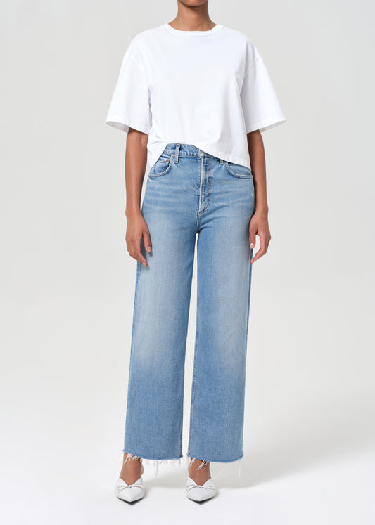 Person wearing a white t-shirt and light blue jeans on a plain background