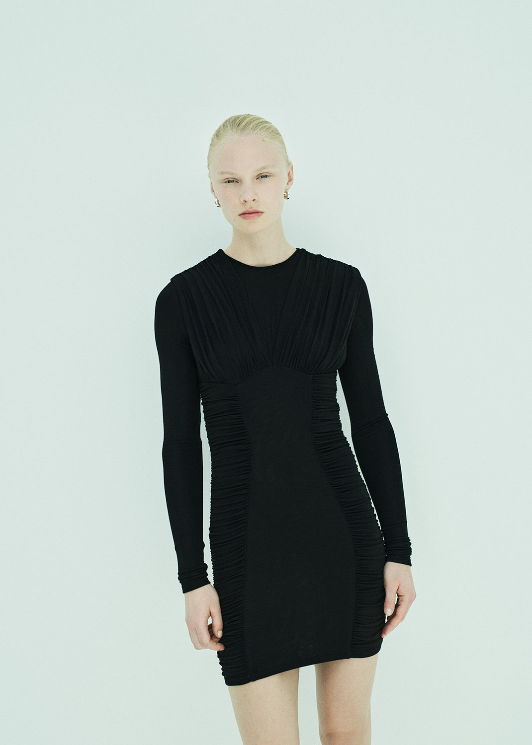 Person wearing a black long-sleeve dress on a light gray background