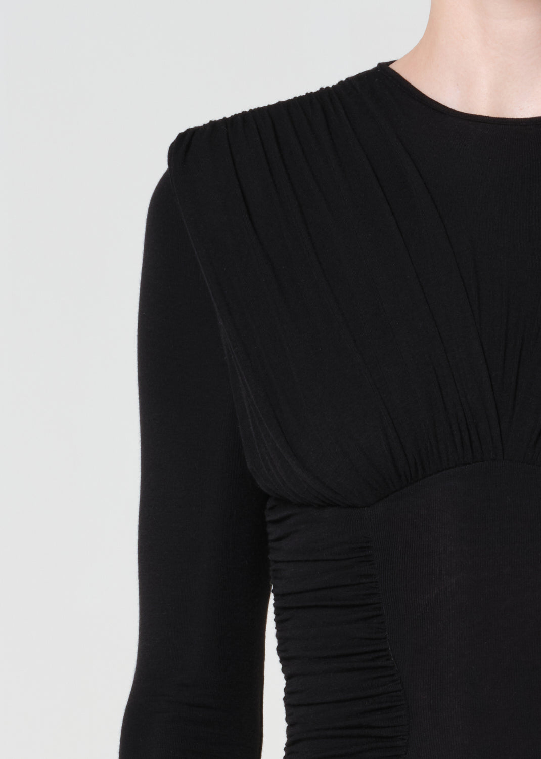Black dress with ruched details on a light gray background