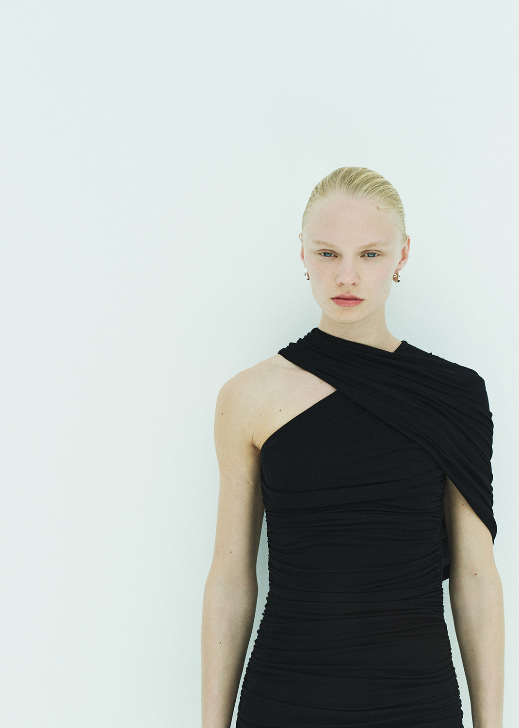 Woman wearing a black one-shoulder dress against a white background
