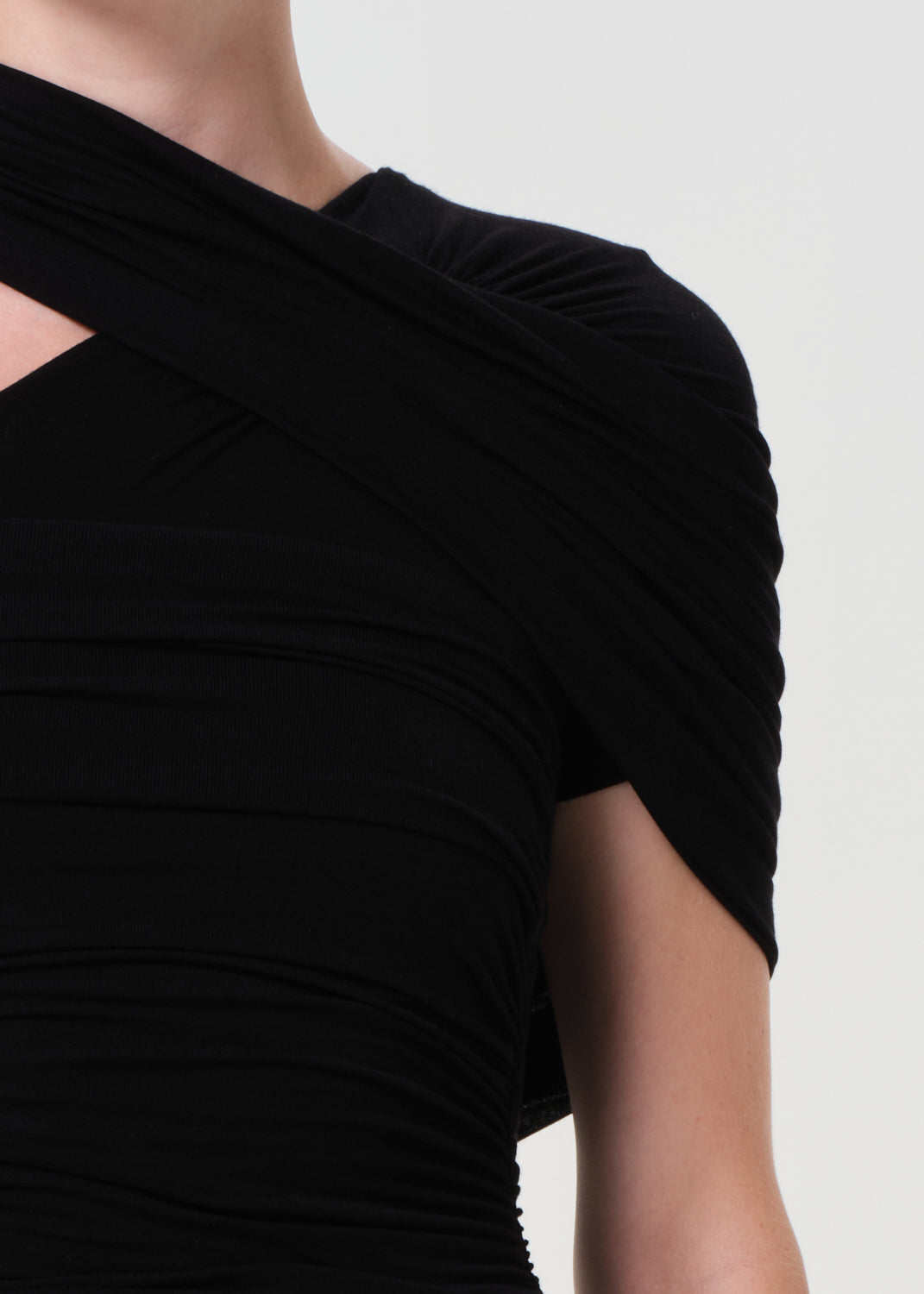 Black dress with a draped design on a plain background