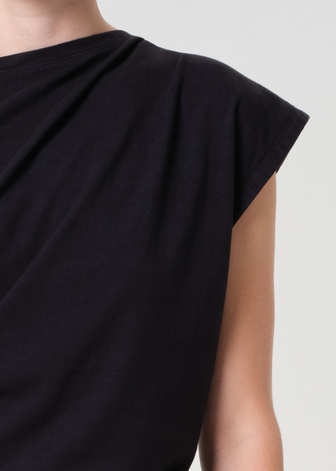 Black sleeveless top worn by a person on a light gray background