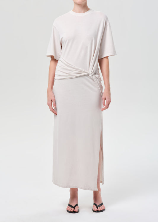 Woman wearing a light-colored dress with a knot detail on a white background