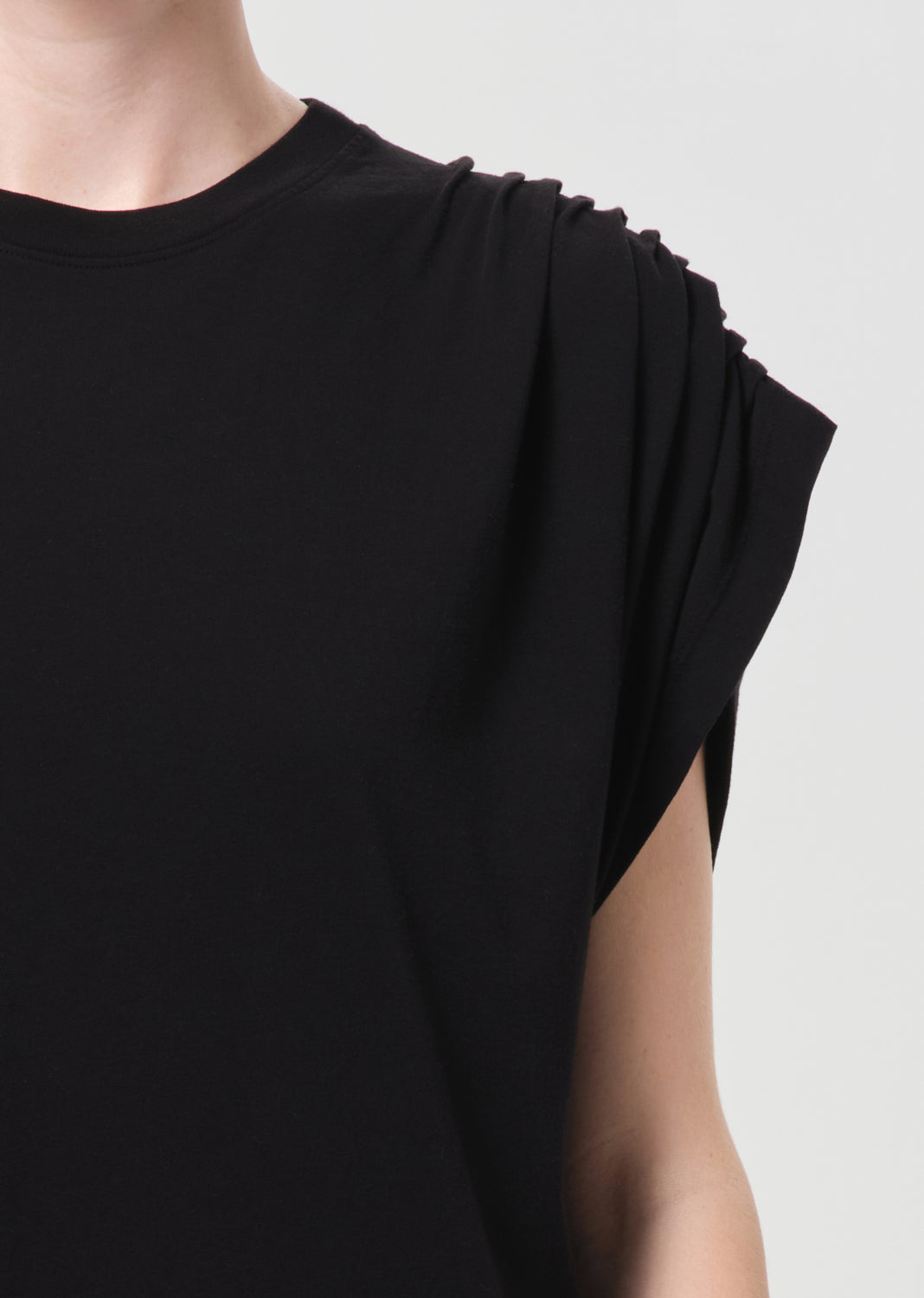 Black dress with draped shoulders on a neutral background