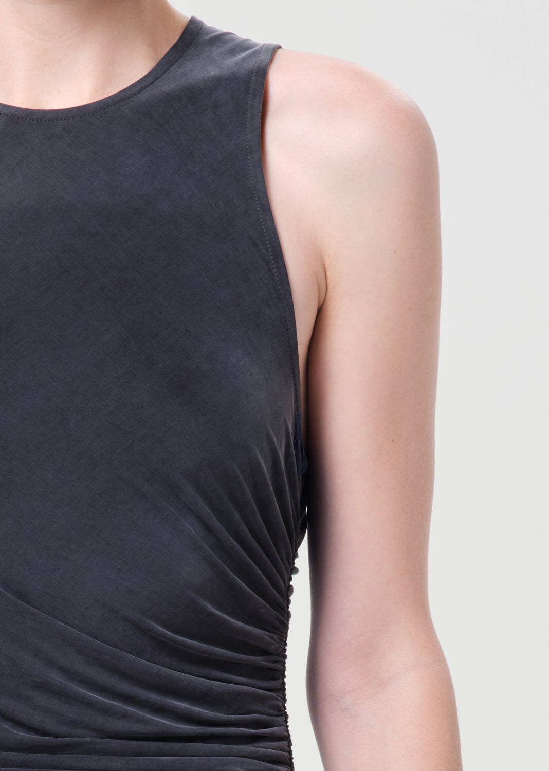 Dark gray sleeveless top worn by a person on a light gray background