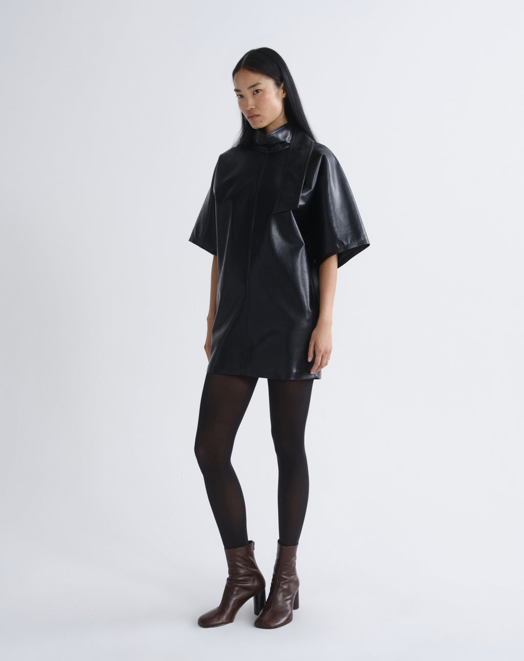 Person wearing a black leather mini dress on a grey background
