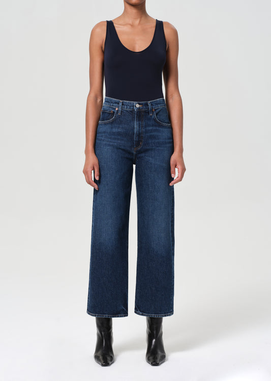Person wearing dark blue jeans and a black tank top on a white background