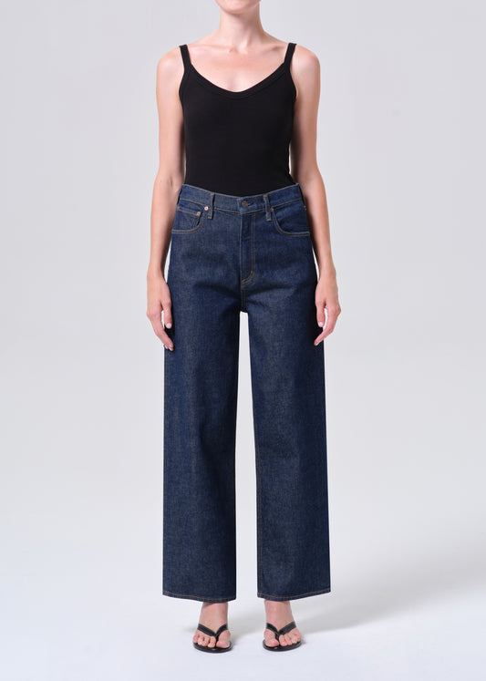 Person wearing dark blue jeans and a black tank top on a white background