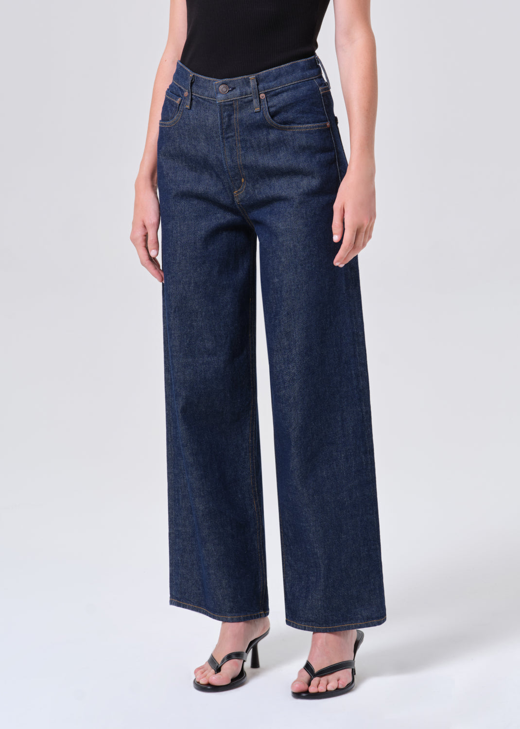 Person wearing dark blue wide-leg jeans on a white background
