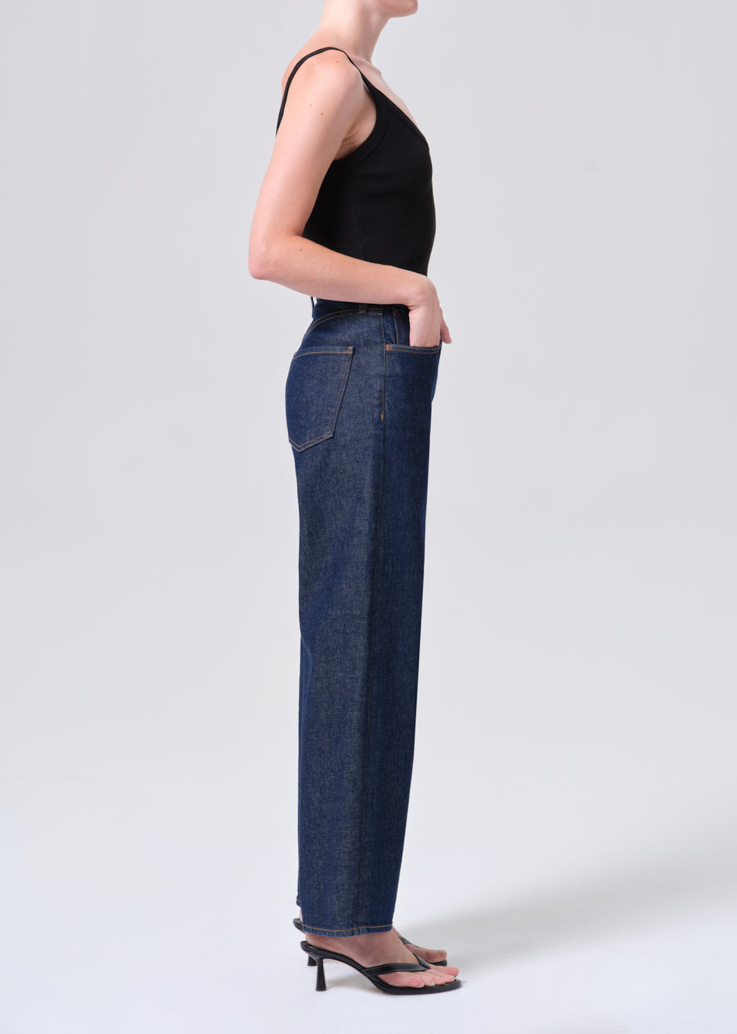 Person wearing dark blue jeans and a black top on a white background