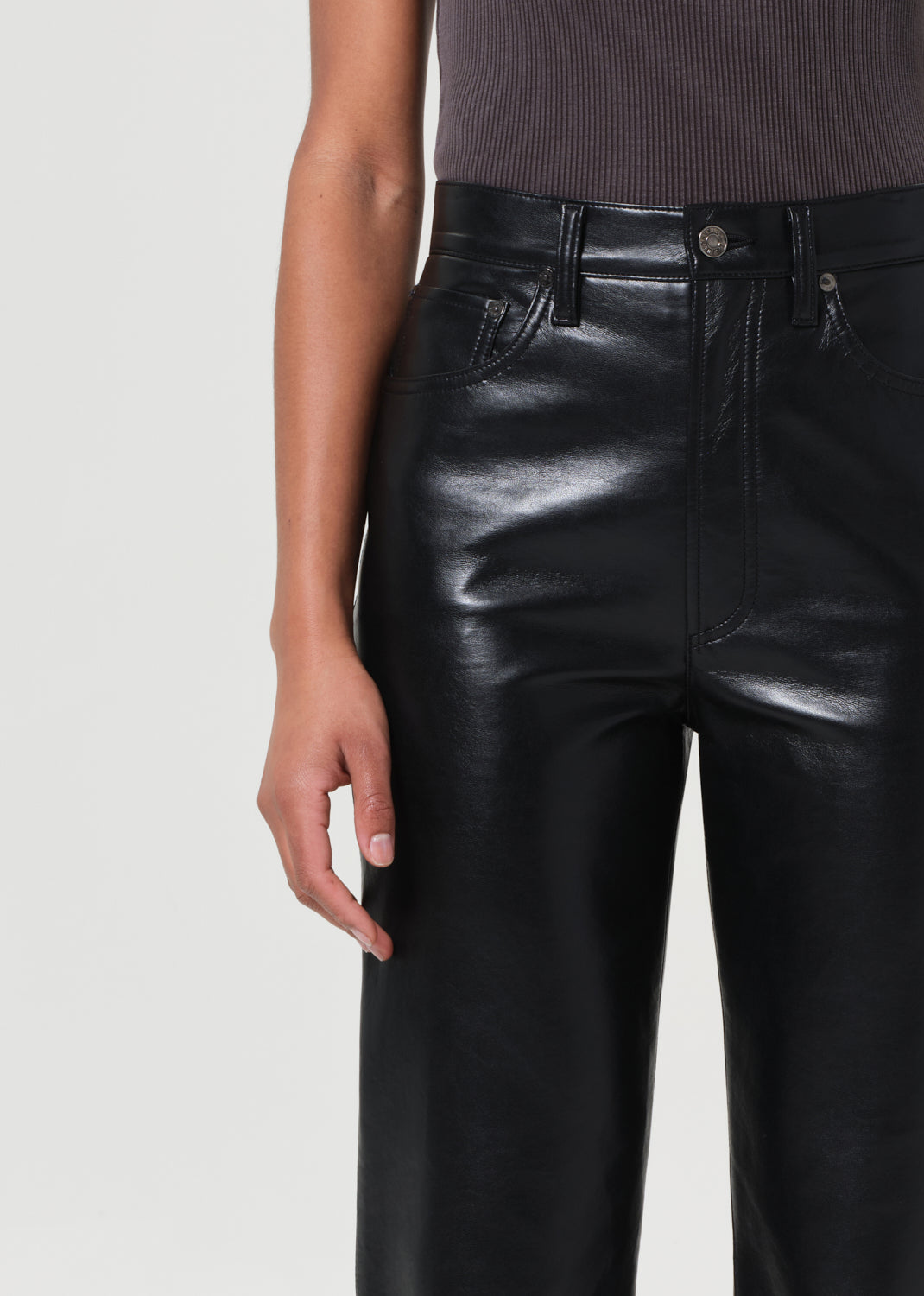 Black leather pants worn by a person on a light gray background