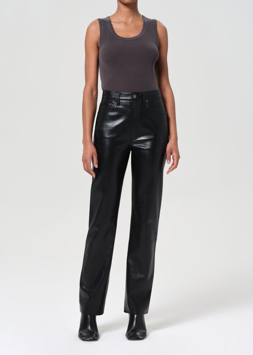Person wearing a gray tank top and black leather pants on a white background