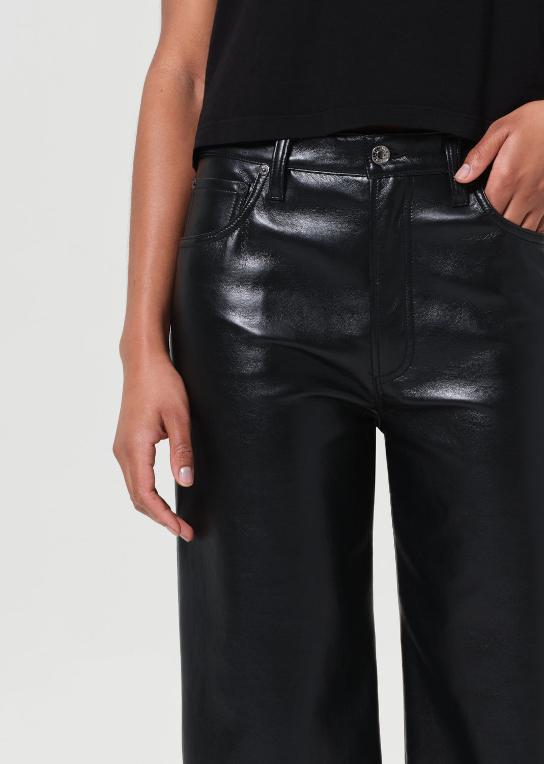 Black leather pants worn by a person on a light gray background