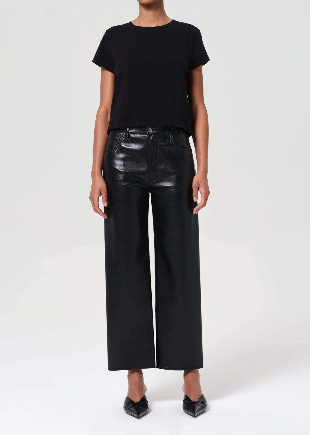 Person wearing a black t-shirt and black leather pants on a white background
