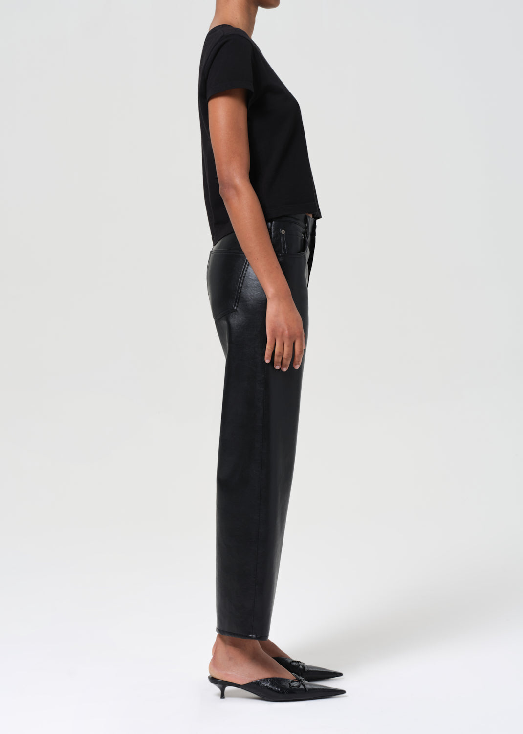 Person wearing black leather pants and a black top on a white background