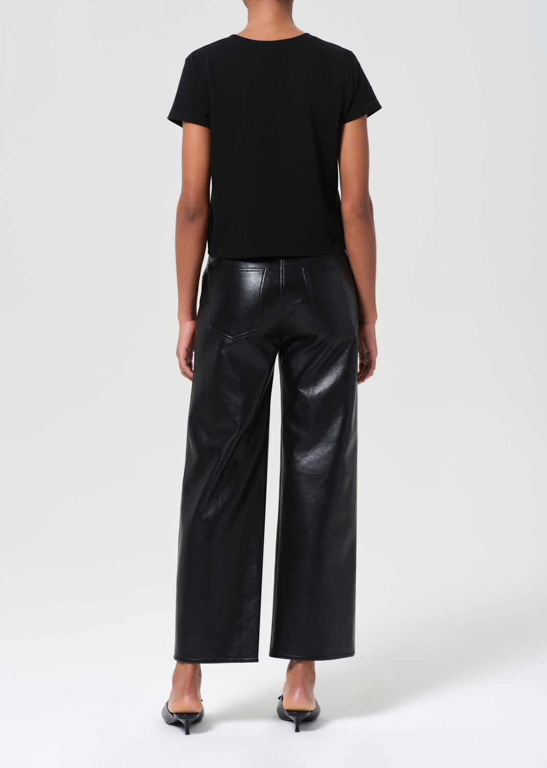 Person wearing black leather pants and a black top on a white background